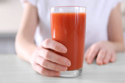 Hand hält frisch gepressten Tomatensaft- www.gesundheitsjournalistin.ch